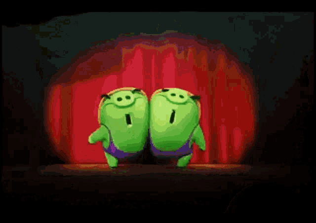 three green pigs wearing hard hats and holding tools are on a stage