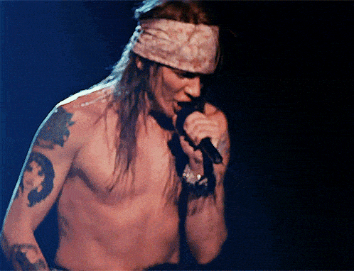 a man without a shirt singing into a microphone