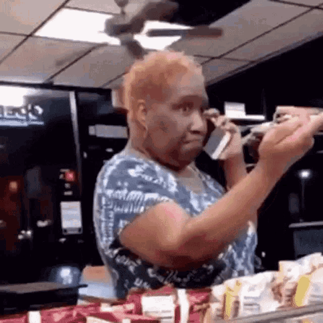 a woman is talking on a cell phone in a store while holding a bottle of soda .