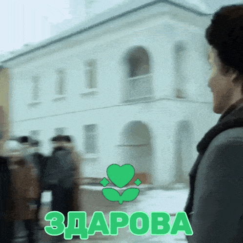 a man walking in front of a building with a green heart and the word zdrava