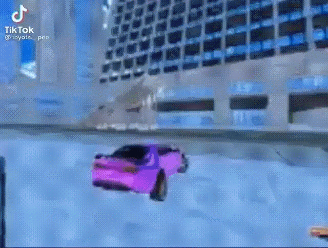 a purple car is driving down a snow covered road in front of a building .