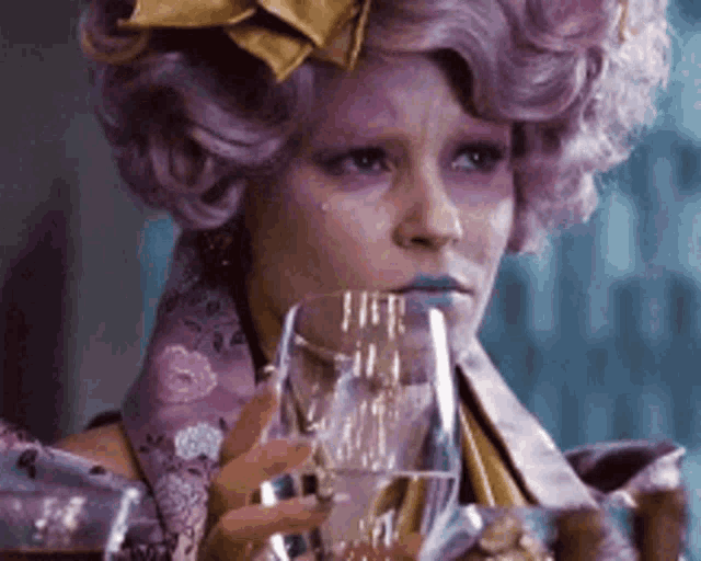 a woman with purple hair is holding a glass of wine and crying .