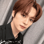 a close up of a young man 's face with red hair wearing a black shirt .