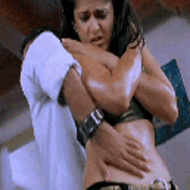a man is holding a woman 's stomach in a room while she is naked .