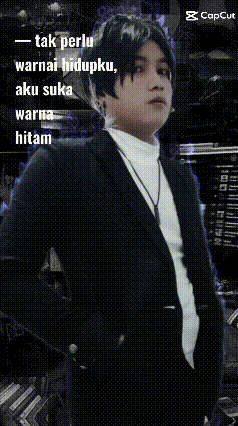 a man in a suit is standing in front of a sign that says tak perlu warna hidupku aku suka warna hitam .