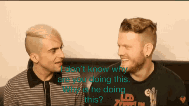 two men are sitting next to each other and one of them is wearing a shirt that says led on it