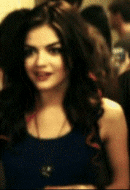 a woman with long dark hair is wearing a blue tank top and a necklace