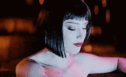 a close up of a woman 's face with her eyes closed and a pink dress on .