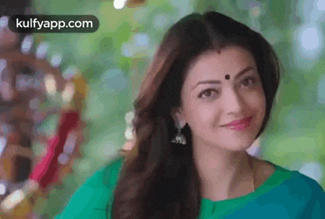 a close up of a woman wearing a green saree and earrings .