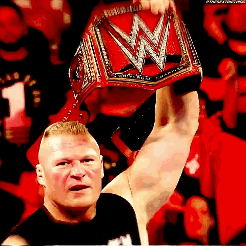 a wrestler is holding up his wwe world heavyweight championship belt in front of a crowd