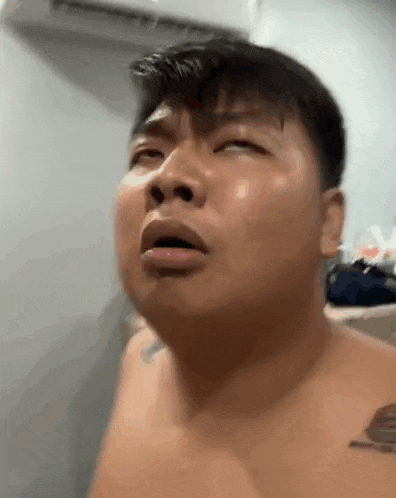 a shirtless man is making a funny face in a bathroom .