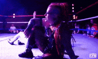 a woman is kneeling down in a wrestling ring .