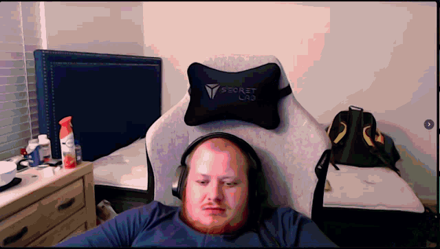 a man wearing headphones is sitting in a chair with a secret lab pillow on it