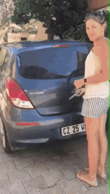 a woman standing in front of a blue hyundai car