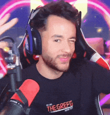 a man wearing headphones and a shirt that says the grefg is sitting in front of a microphone