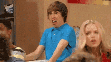a boy in a blue shirt is making a funny face while sitting on a bed .