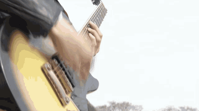 a close up of a person playing an electric guitar outdoors
