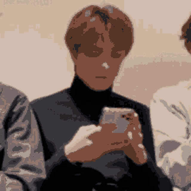 a man in a black turtleneck looks at his phone