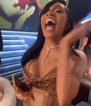 a woman in a gold dress is laughing with her mouth open and holding a banana .