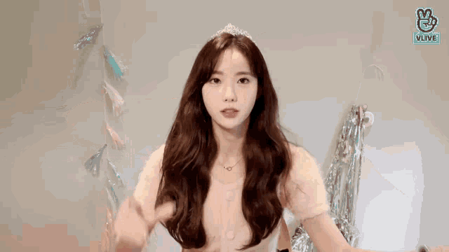a woman wearing a tiara and a watch is making a heart shape with her hands