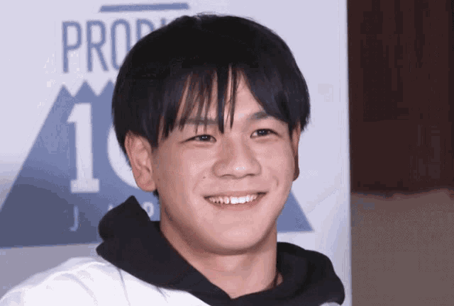 a young man smiles in front of a sign that says pro