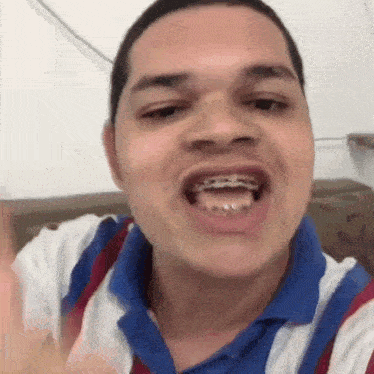 a man with braces on his teeth is making a funny face while sitting on a couch .