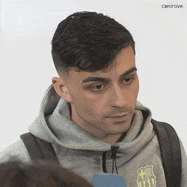 a man wearing a grey sweatshirt with fcb on it