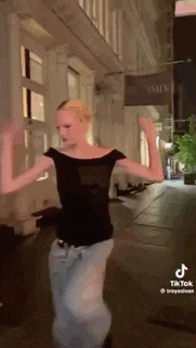 a woman is dancing in front of a building on a city street .