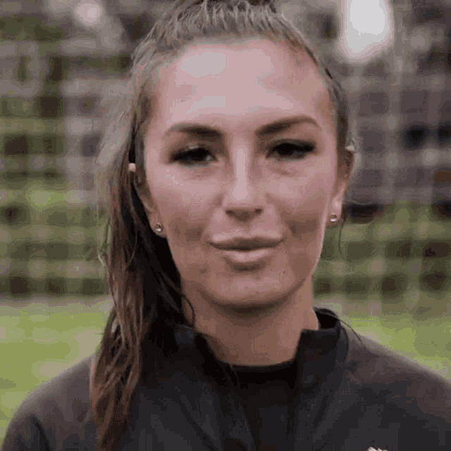 a close up of a woman 's face with a ponytail and earrings