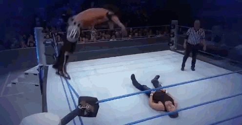 a man is laying on the ground in a wrestling ring with a referee in the background