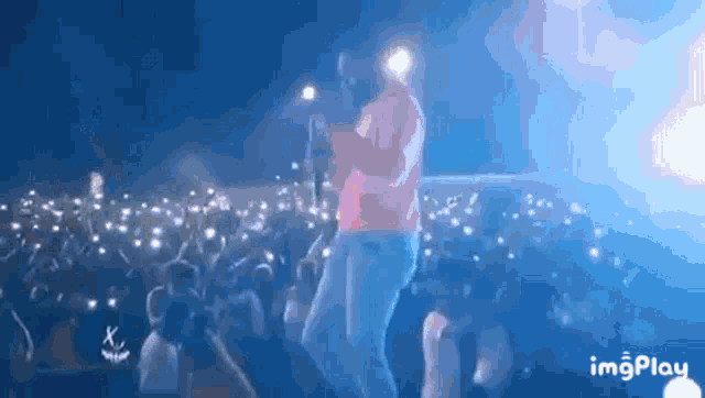 a man is singing into a microphone in front of a crowd of people with their hands in the air ..