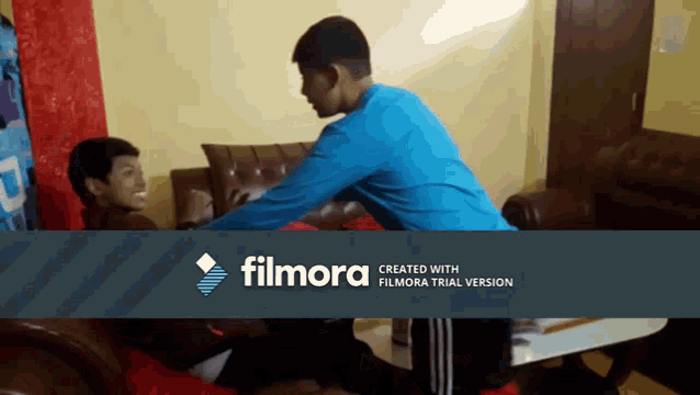 a man in a blue shirt is standing next to another man in a living room with a filmora logo in the corner
