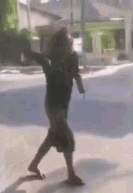 a man in a black shirt and shorts is walking on a sidewalk .