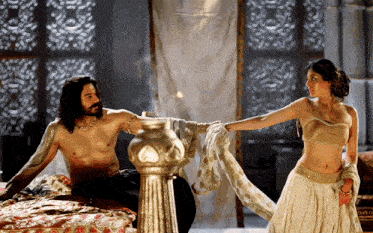 a man is sitting on a bed with a woman standing next to him
