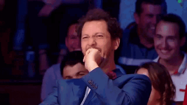 a man in a suit is laughing in a crowd of people .