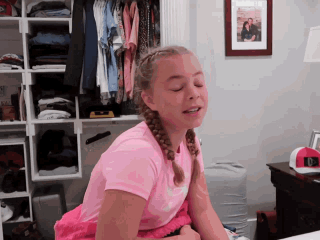 a girl in a pink shirt is sitting in front of a picture of a couple
