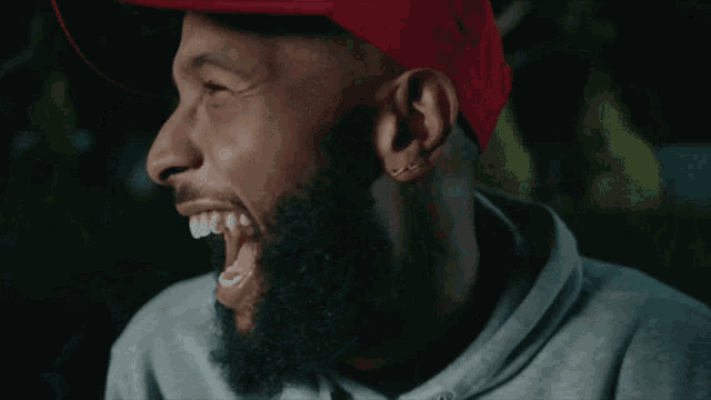 a man with a beard and a red hat is laughing
