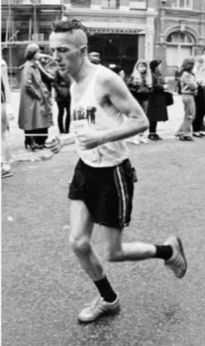 a man wearing a white tank top with the word army on it is running down the street