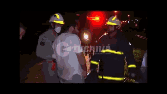 a group of firefighters are standing next to each other in front of a red light that says ' g ' on it
