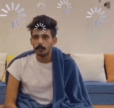 a man with a mustache is sitting on a couch with a blue blanket over his head .