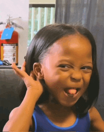 a little girl in a blue tank top is making a funny face and sticking her tongue out