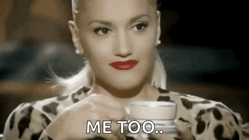 a woman is holding a cup of coffee in her hand and saying `` me too '' .