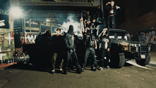 a group of people are standing in front of a jeep that says ' hn ' on the license plate