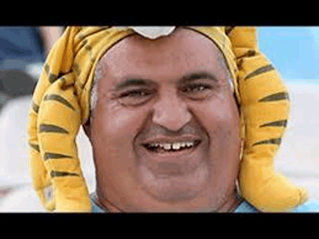 a man wearing a tiger hat is smiling and looking at the camera .
