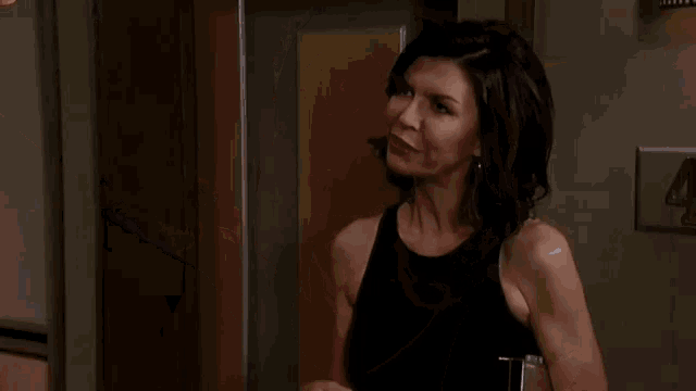 a man and a woman are kissing in a room . the woman is wearing a black dress .