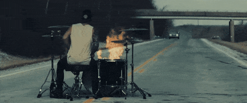 a man playing drums in the middle of a road