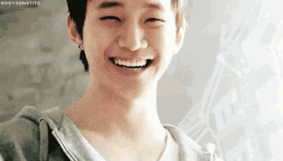 a young man is smiling with his eyes closed and his teeth showing .