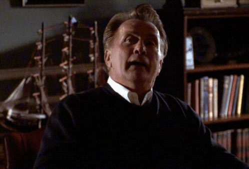 a man in a black sweater holds a baseball in his hand