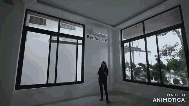 a woman stands in a room with a sign that says bedroom # 1 on it