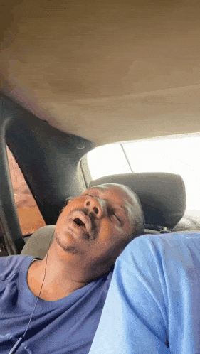 a man sleeping in a car with his mouth open